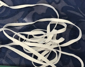 Puede incluir: Banda elástica blanca, un tipo de cordón elástico utilizado para coser y proyectos de manualidades.