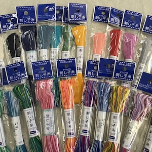 May include: Assortment of colourful embroidery floss spools in individual clear plastic packaging. Each spool is labelled "Olympus 刺し子糸" which translates to "Olympus Sashiko Thread".