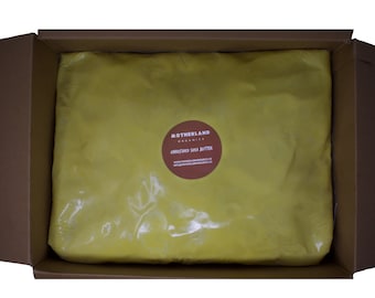 May include: A large block of unrefined shea butter in a cardboard box. The shea butter is wrapped in clear plastic and has a label that reads "MOTHERLAND ORGANICS UNREFINED SHEA BUTTER www.motherlandorganics.co.uk".