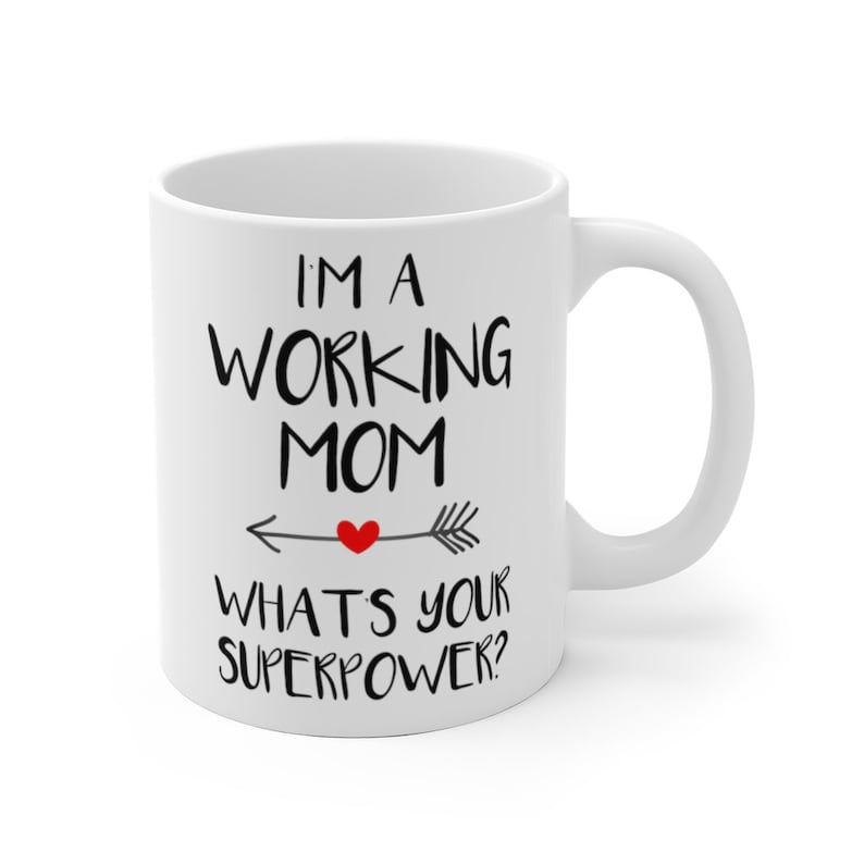 Puede incluir: Taza de cer&aacute;mica blanca con el texto "I'M A WORKING MOM WHAT'S YOUR SUPERPOWER?" en escritura negra. Un coraz&oacute;n rojo est&aacute; en el centro de una flecha que apunta hacia la izquierda. La taza tiene un asa curva.