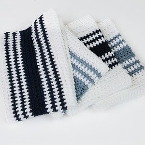 May include: Four crocheted dishcloths in white, blue, and black with a striped pattern.