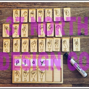 May include: Wooden alphabet tiles with sign language illustrations for each letter. The tiles are arranged in alphabetical order. A wooden board with the word "PLAY" spelled out in white letters and sign language illustrations for each letter. A dry erase marker is included.