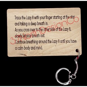 May include: Wooden keychain with a light brown finish and a silver metal ring. The keychain features a printed message: "Trace the Lazy 8 with your finger starting at the star and taking a deep breath in. As you cross over to the other side of the Lazy 8, slowly let your breath out. Continue breathing around the Lazy 8 until you have a calm body and mind."