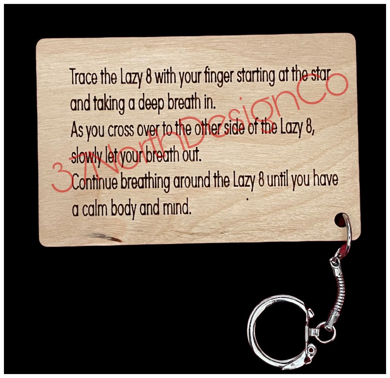 May include: Wooden keychain with a light brown finish and a silver metal ring. The keychain features a printed message: "Trace the Lazy 8 with your finger starting at the star and taking a deep breath in. As you cross over to the other side of the Lazy 8, slowly let your breath out. Continue breathing around the Lazy 8 until you have a calm body and mind."