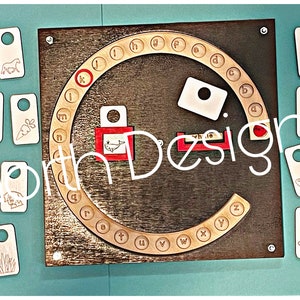 May include: A wooden alphabet wheel with a red circle around the letter K. There are 26 white wooden tags with various images on them, including a pig, a grape, a horse, a sheep, a clock, a fish, a chair, a cloud, and a tree.