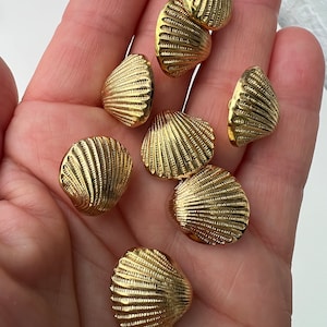 May include: Eight gold-coloured shell-shaped buttons with a textured surface.
