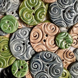 May include: A collection of ceramic buttons with a swirl design in various colours, including green, blue, and brown.
