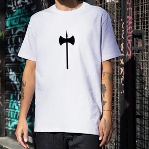 May include: White t-shirt featuring a black axe graphic. The axe design is centered on the chest. The shirt is made of a soft, opaque material. The model is wearing black pants.
