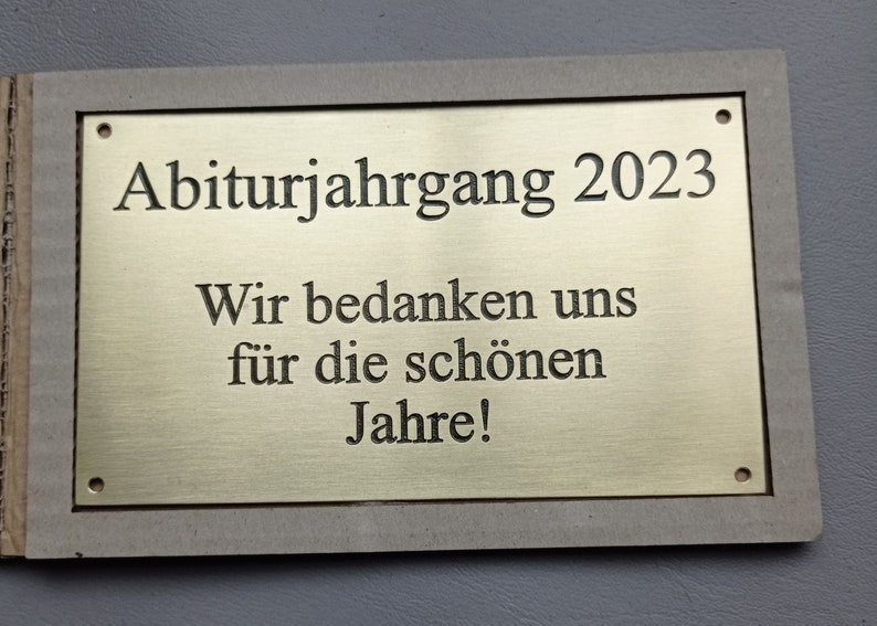 May include: A gold plaque with the text "Abiturjahrgang 2023" and "Wir bedanken uns f&uuml;r die sch&ouml;nen Jahre!"