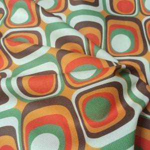 May include: A fabric with a retro pattern of overlapping circles and squares in shades of orange, brown, green, and white.