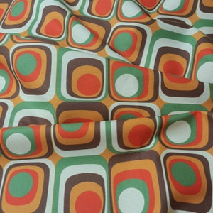 May include: A fabric with a repeating pattern of squares and circles in shades of brown, orange, green, and white.
