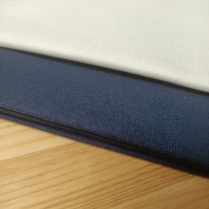 Puede incluir: Dos muestras de tela, una de color beige claro y la otra de color azul marino oscuro. Las muestras est&aacute;n dobladas y superpuestas.