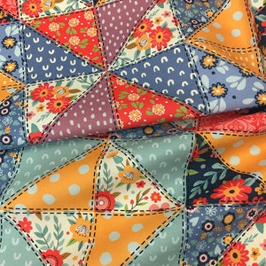May include: Close-up of a patchwork fabric with a variety of colorful patterns. The design features triangles with floral, polka dot, and solid patterns in shades of blue, orange, red, and purple. The triangles are stitched together with black thread.