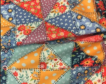 May include: Close-up of a patchwork fabric with a variety of colorful patterns. The design features triangles with floral, polka dot, and solid patterns in shades of blue, orange, red, and purple. The triangles are stitched together with black thread.