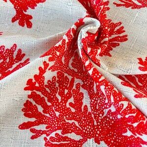 May include: White fabric with a red coral print. The fabric is textured and has a woven look.
