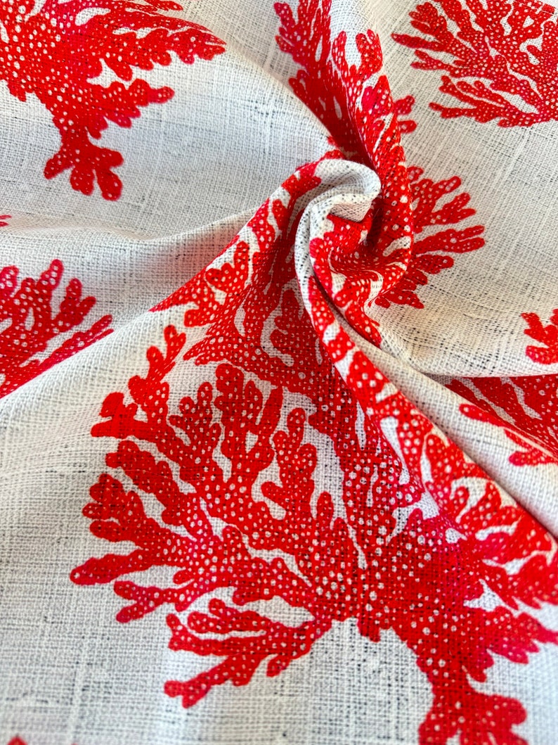 May include: White fabric with a red coral print. The fabric is textured and has a woven look.