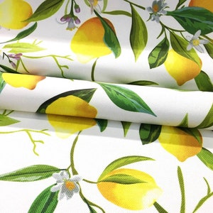 May include: White fabric with a repeating pattern of yellow lemons and green leaves. The lemons are arranged in a diagonal pattern and the leaves are arranged in a vertical pattern.