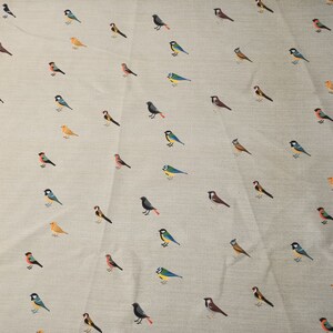 May include: A beige fabric with a repeating pattern of various colorful birds. The birds are all different species and are arranged in a random pattern.