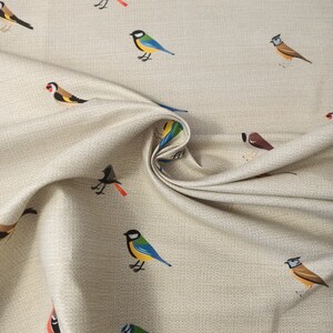 May include: Beige fabric with a repeating pattern of colorful birds. The birds are in various poses, including flying, perched, and singing. The fabric has a subtle texture.