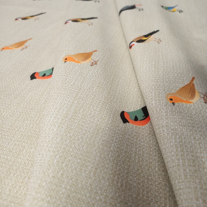 May include: Beige fabric with a repeating pattern of colorful birds. The birds are in various poses, including flying, perched, and singing.