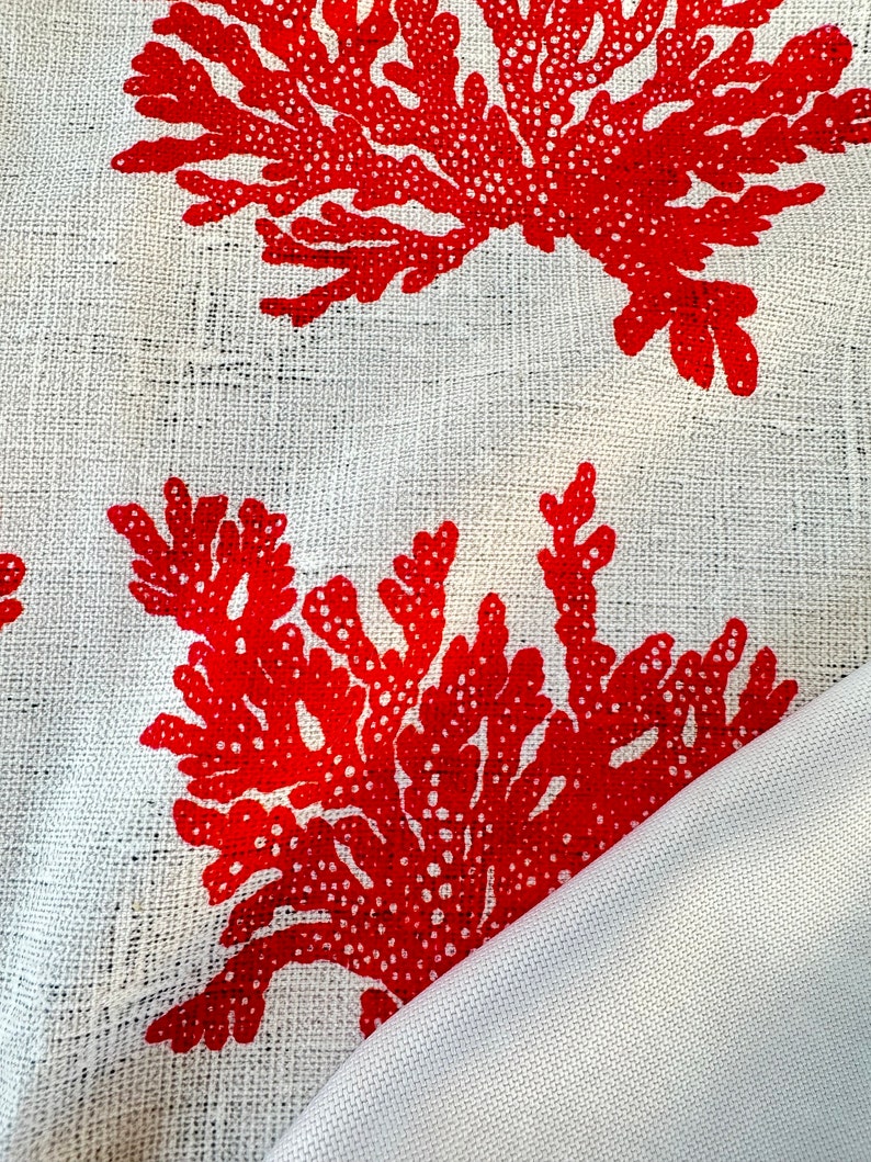 May include: Red coral print on a white linen fabric. The fabric is folded over, showing the white underside.