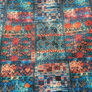 May include: A colorful fabric with a patchwork design featuring various geometric patterns in shades of blue, red, orange, and white.