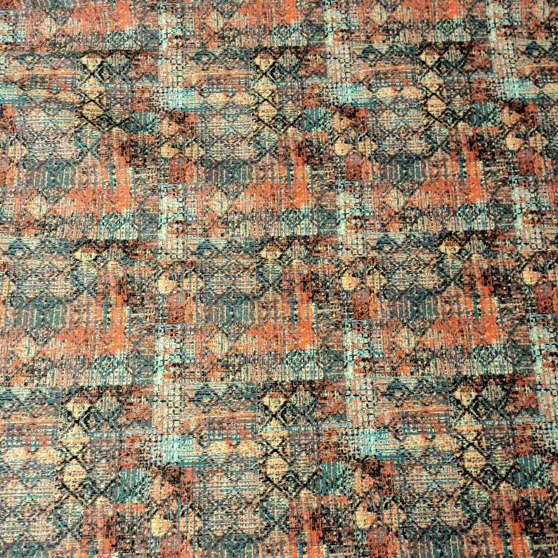 May include: A close-up of a fabric with a geometric pattern in shades of orange, teal, and brown. The fabric has a textured, woven look.