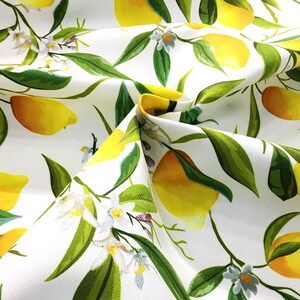 May include: White fabric with a repeating pattern of yellow lemons, green leaves, and white flowers.