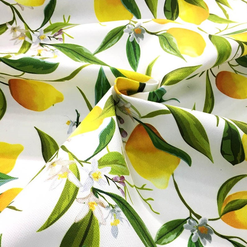May include: White fabric with a repeating pattern of yellow lemons, green leaves, and white flowers.