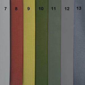 Puede incluir: Primer plano de siete muestras de tela en diferentes colores. Las muestras est&aacute;n numeradas del 7 al 13. Los colores son gris claro, rojo, amarillo, verde, verde oscuro, gris y azul.