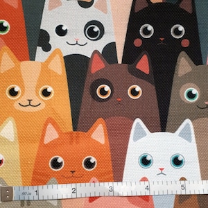 May include: A colorful fabric with a repeating pattern of cartoon cats. The cats are in various colors, including orange, brown, black, white, and gray. The fabric is measured with a ruler, showing a length of 5 inches.