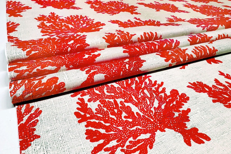 May include: Red coral reef print fabric with a white background. The fabric is folded and shows the pattern repeating.