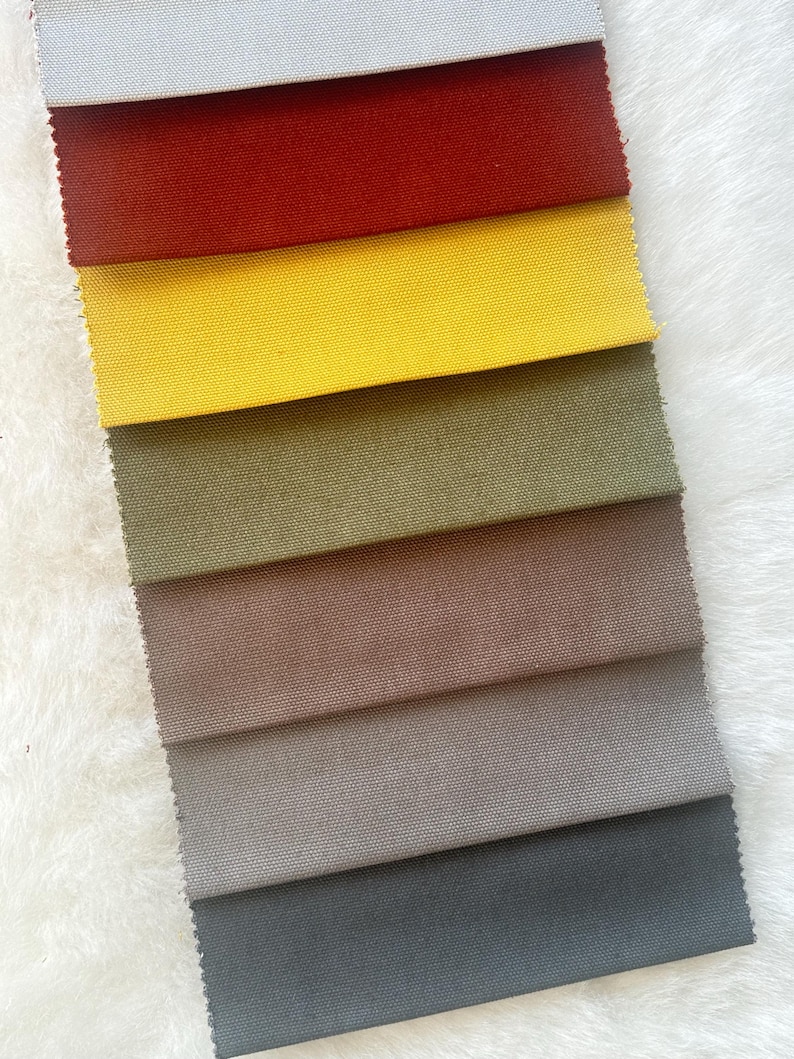 Puede incluir: Una colecci&oacute;n de ocho muestras de tela en diferentes colores, incluyendo gris, rojo, amarillo, verde, marr&oacute;n, beige, gris oscuro y negro. Las muestras est&aacute;n dispuestas en una pila vertical, con la muestra gris en la parte superior y la muestra negra en la parte inferior.