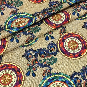 May include: Close-up of a fabric with a repeating pattern of colorful paisley and circular designs. The pattern features shades of blue, green, orange, and purple on a tan background. The fabric has a textured appearance.
