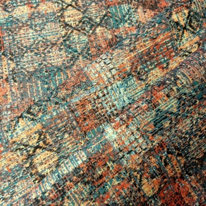 May include: A close-up of a fabric with a colorful, abstract pattern. The fabric is a blend of orange, blue, and black colors, creating a textured and intricate design.