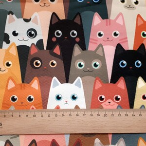 May include: A colorful fabric with a repeating pattern of cartoon cats in various colors and poses. The cats are all facing forward and have large eyes. The fabric is a great choice for crafting projects, quilting, or making clothing.