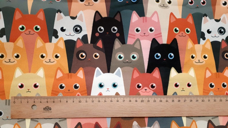 May include: A colorful fabric with a repeating pattern of cartoon cats in various colors and poses. The cats are all facing forward and have large eyes. The fabric is a great choice for crafting projects, quilting, or making clothing.