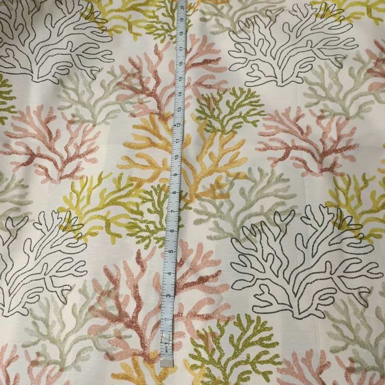 Puede incluir: Tela blanca con un patr&oacute;n repetitivo de ramas de coral en tonos de rosa, verde y amarillo. La tela se mide con una cinta m&eacute;trica.