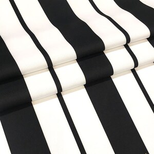 May include: Black and white striped fabric with a smooth texture. The fabric is folded in thirds, showing the pattern.