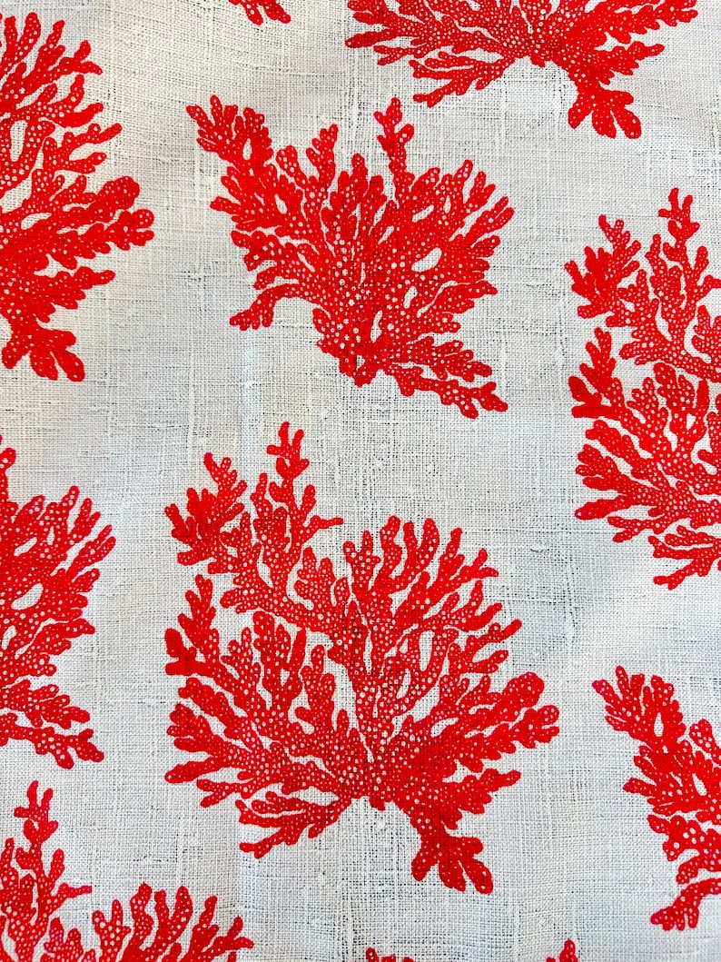 May include: Red coral reef pattern on a white linen fabric. The coral is a stylized design with a repeating pattern.