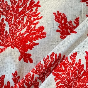 May include: White fabric with a red coral pattern. The fabric has a textured woven look.