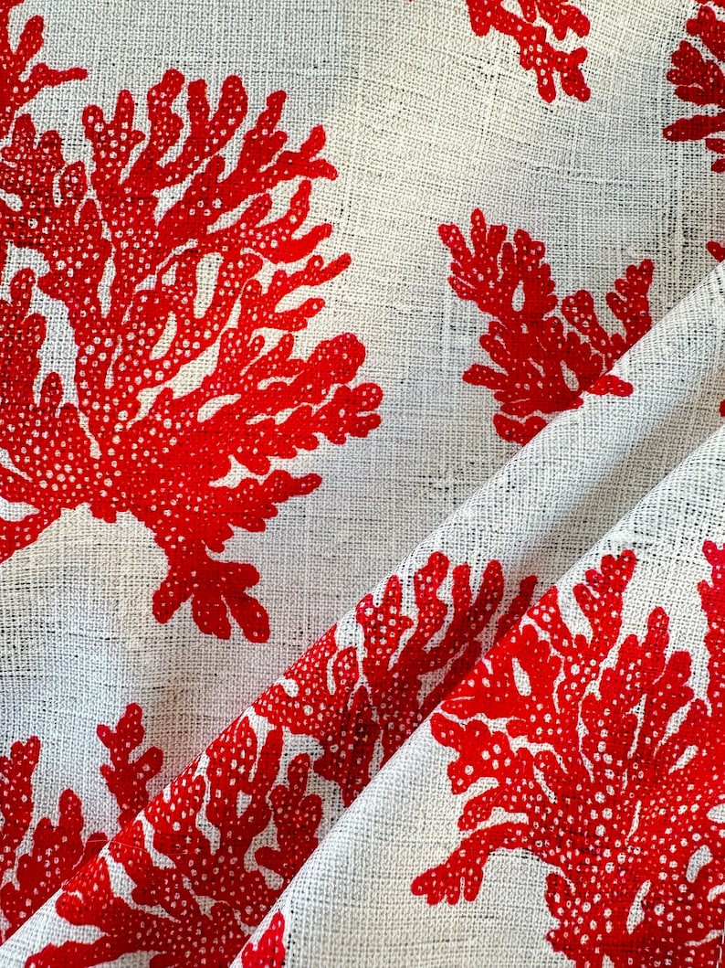 May include: White fabric with a red coral pattern. The fabric has a textured woven look.