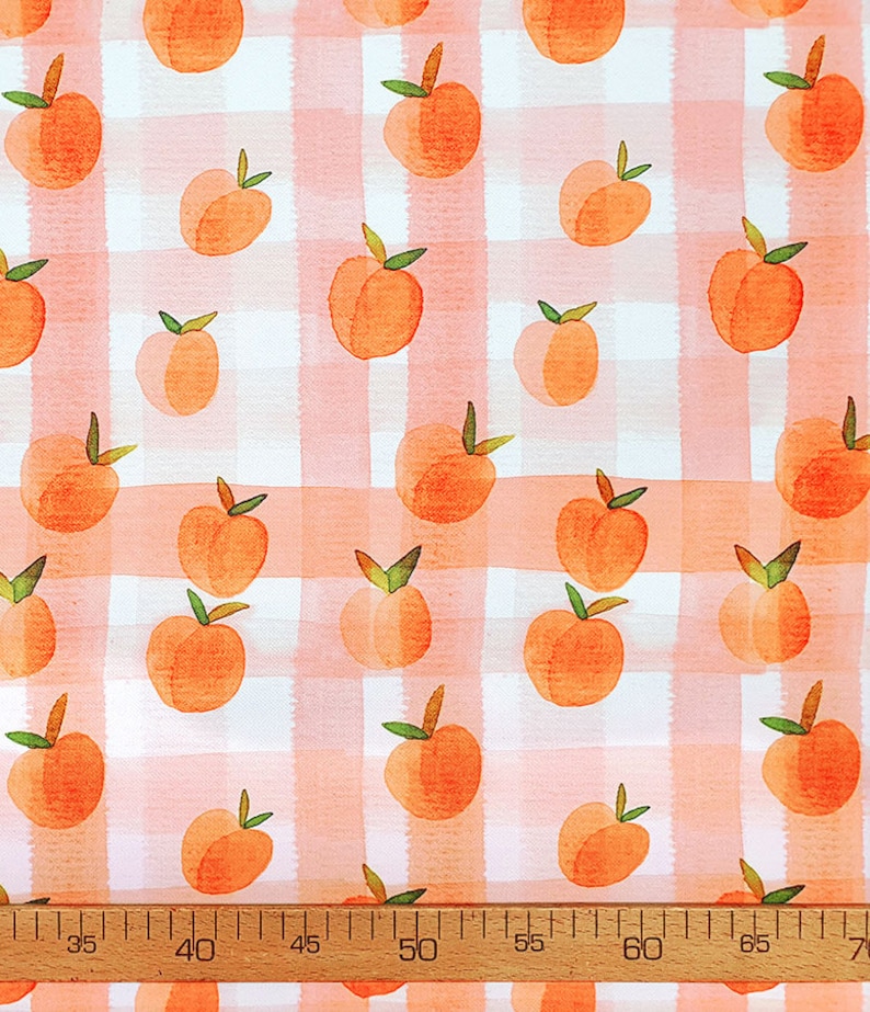 May include: Peach print fabric with a pink and white gingham pattern. The fabric features a repeating pattern of peaches with green leaves.