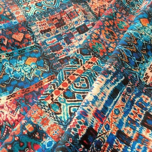 May include: A colorful fabric with a geometric pattern in shades of blue, orange, red, and white. The fabric has a woven texture and is perfect for crafting projects.