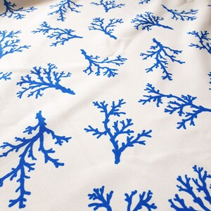 Peut inclure: Tissu blanc avec un motif répétitif de branches de corail bleues.