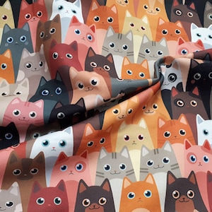 May include: A colorful fabric with a repeating pattern of cartoon cats in various colors and poses. The cats are all looking at the viewer with big eyes and smiling.