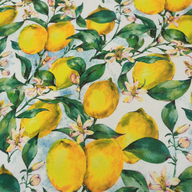 May include: A white background with a repeating pattern of yellow lemons and green leaves. The lemons are arranged in a random pattern and are surrounded by green leaves. The background is a light blue color.
