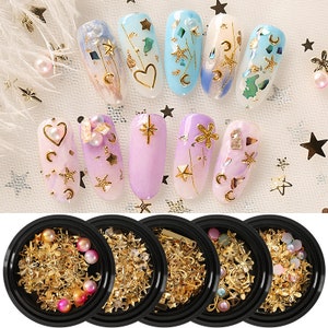 May include: Set of four nail art containers with assorted gold and silver glitter, stars, and other decorative elements. The containers are black with a clear lid.
