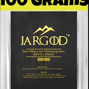 May include: A black pouch with a yellow label that reads "100 GRAMS" and "JARGOD" in yellow text. The pouch contains a refill pack of hair fibers for thinning hair, available in 50g and 100g sizes. The ingredients are Gossypium Herbaceum Fiber and mineral-based colorants. The label also includes a caution statement.