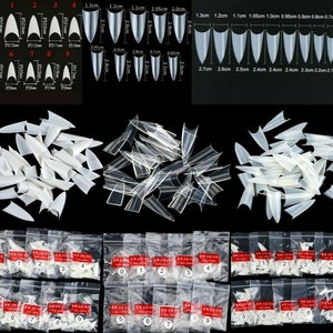 May include: A set of 10 bags of clear plastic false nail tips in various sizes and shapes. Each bag is labeled with a number from 0 to 9. The nail tips are arranged in rows and columns on a black background.